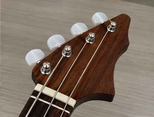 Close-up of the guitar's headstock and tuning pegs, made from a dark hardwood with a bone nut